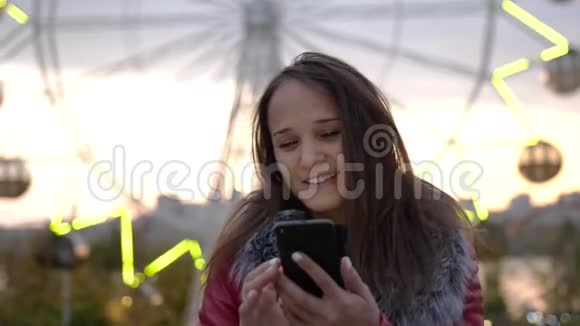 美丽的黑发年轻女子在夜间小镇的街道上散步时使用手机灯光很漂亮慢慢视频的预览图