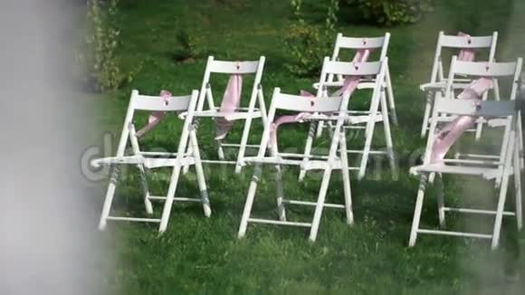 白色的椅子粉红色的蝴蝶结在风中飘扬露天登记的婚礼装饰视频的预览图