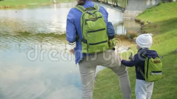 一家人正在湖边的公园里喂鸭子这个小男孩帮助把食物给鸟扔进水里视频的预览图
