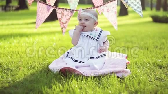 阳光明媚的夏日可爱的小女孩坐在草地上视频的预览图