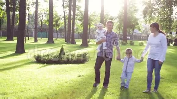 快乐的年轻家庭一起在外面度过绿色的夏日公园视频的预览图
