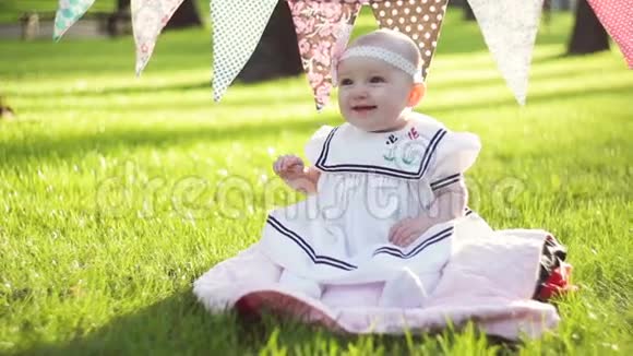 阳光明媚的夏日可爱的小女孩坐在草地上视频的预览图