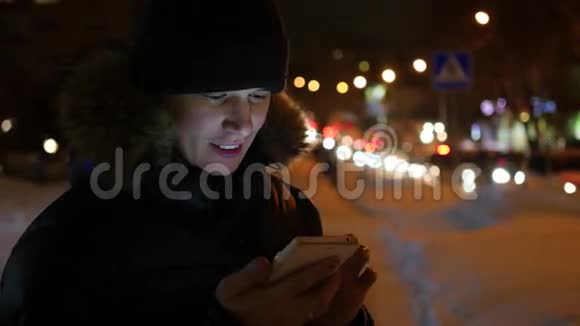 在城市的夜晚冬天的时候人们在智能手机上视频的预览图