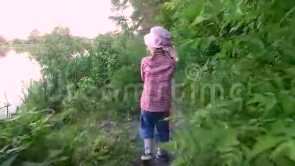 小女孩走在池塘岸边的一条狭窄的小路上视频的预览图