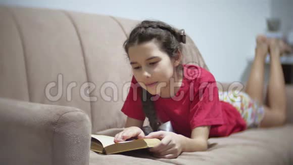 十几岁的女孩躺在沙发上看书躺在室内沙发上看书的女孩视频的预览图