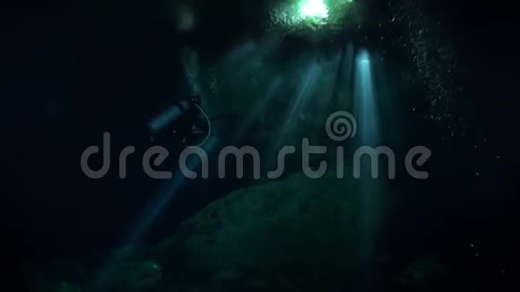 在墨西哥尤卡坦的黑暗洞穴里用手电筒游泳视频的预览图