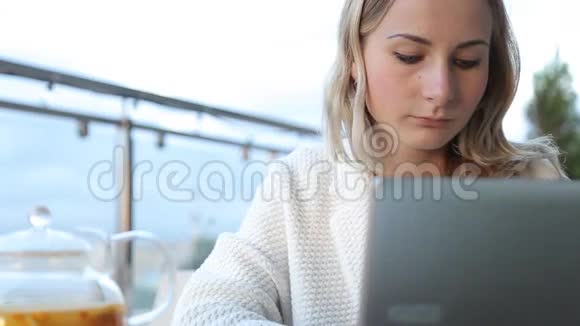 女人在现代笔记本电脑上工作在咖啡馆喝茶视频的预览图