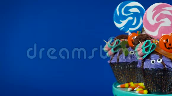 万圣节糖果滴蛋糕风格的纸杯蛋糕与糖果在蓝色背景视频的预览图