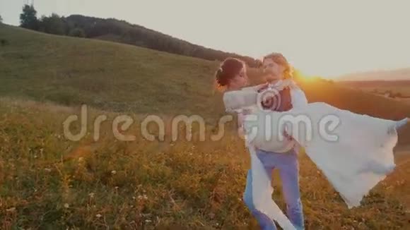 年轻的一对拥抱着在夕阳下旋转着视频的预览图