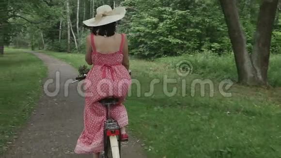 穿着夏装戴着帽子的年轻女子骑着自行车穿过公园动作缓慢运动价值高视频的预览图