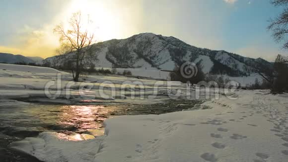 河流流动在夕阳下闪闪发光在山里寒冷的冬天视频的预览图