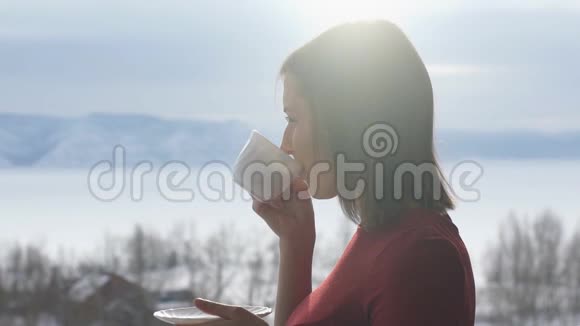 女人在阳台上喝咖啡背景是群山视频的预览图