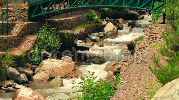 阳光明媚的一天热带山河有小瀑布和装饰桥视频的预览图