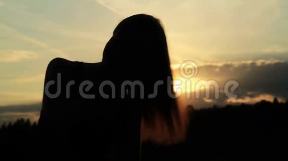 一个女人在夕阳下梳头的剪影视频的预览图