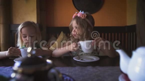 两个可爱的金发小女孩在舒适的咖啡馆里喝茶视频的预览图