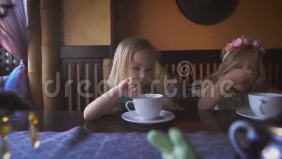 两个可爱的小女孩在舒适的咖啡馆里喝茶视频的预览图