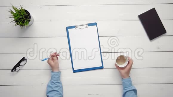从上图可以看到男性手拿笔手拿纸夹在书桌上视频的预览图