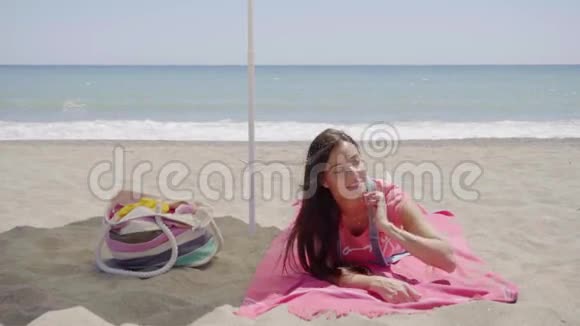 可爱的女人躺在沙滩毛毯上视频的预览图