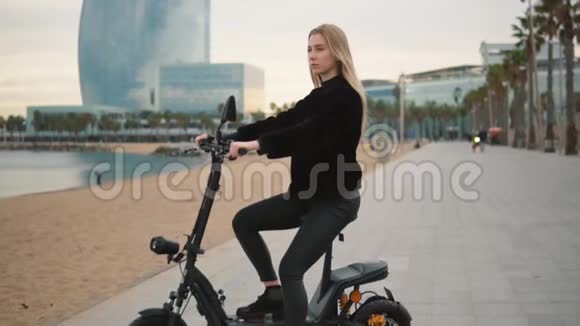 漂亮的金发女郎在海边驾驶电动自行车视频的预览图