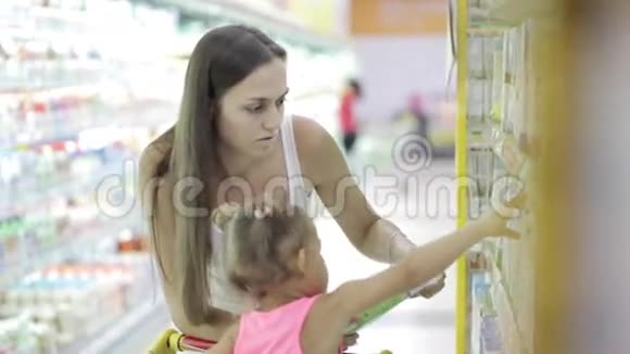年轻女子带着可爱的女儿在杂货店买牛奶视频的预览图