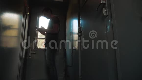 那个人的轮廓站在火车车厢上手里拿着一部智能手机慢动作视频男人写字视频的预览图