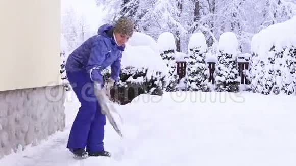 雪后在自己家附近铲雪的年轻女性视频的预览图