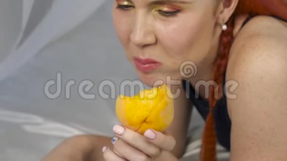 红发女人躺在床上吃新鲜水果健康的早餐慢动作视频的预览图