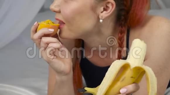 红发女人躺在床上吃新鲜水果健康的早餐慢动作视频的预览图