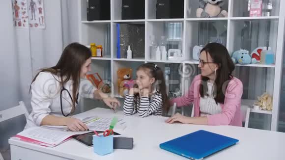 一个女人带着一个年轻的女儿在办公室和一位儿科医生交谈视频的预览图