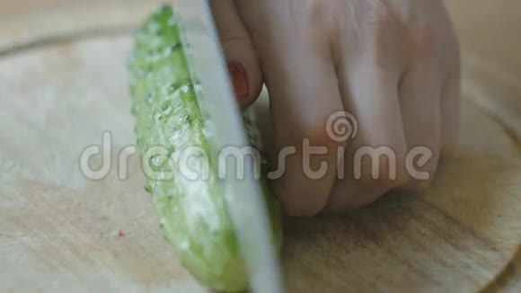 女孩用红指甲把黄瓜切成薄片视频的预览图
