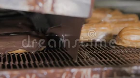 在一家面包店的传送带上融化的巧克力在新鲜的奶油蛋糕上流动视频的预览图