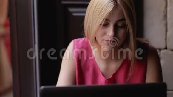 年轻女孩拿着笔记本电脑坐在咖啡馆里视频的预览图