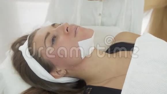 美容师双手合拢将少女下巴用条条在沙龙中舒展视频的预览图