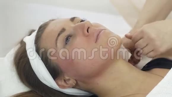 美容师双手合拢使美容院女孩颈部下垂视频的预览图
