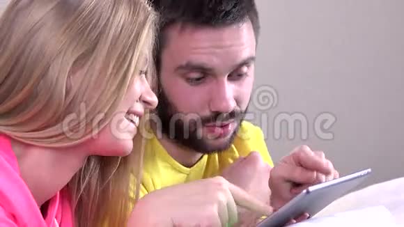 年轻的幸福夫妇在平板电脑上看东西特写视频的预览图