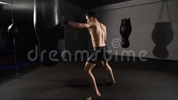 肌肉英俊的拳击手在练习时用拳击袋向前踢一脚视频的预览图