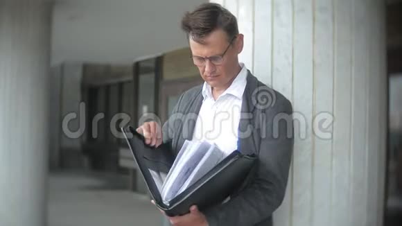 一个年轻可敬的商人被送到一座办公楼他手里拿着一个公文包翻阅文件视频的预览图