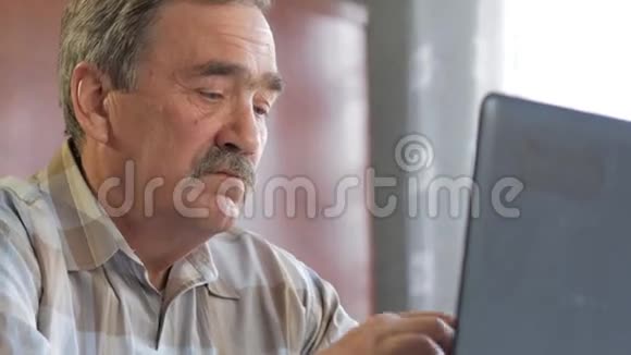 一个有胡子的老人坐在笔记本电脑后面解决问题他认真地看着班长视频的预览图
