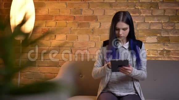 使用平板电脑拍摄年轻美丽的白种人女性的特写肖像并在舒适的家中展示绿色屏幕拍摄视频的预览图