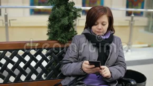 坐在长凳上用智能手机的女人视频的预览图