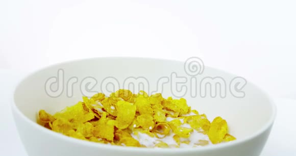 谷物玉米片落在碗中牛奶倒在白色背景下饮食健康食品的概念视频的预览图