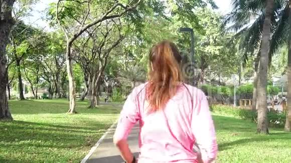 慢动作年轻的亚洲女人早上在人行道上跑步年轻的亚洲运动女子在公园里跑步视频的预览图