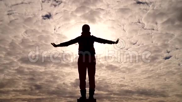一个女孩站着的剪影像鸟一样举起双手飞向天空视频的预览图