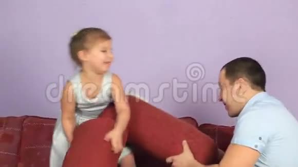 快乐的父亲和女儿在沙发上打枕头视频的预览图