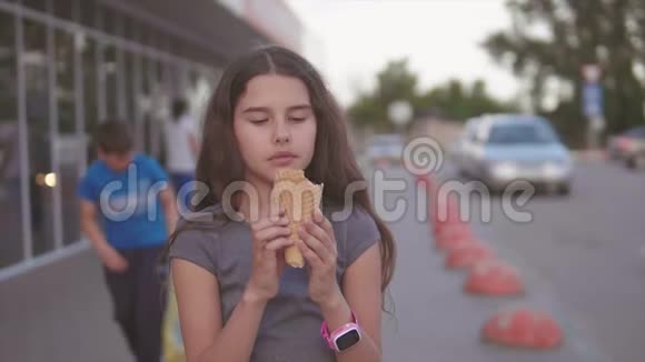 吃冰淇淋的小女孩走在超市旁边的大街上手里拿着一个柔软的玩具慢动作视频的预览图
