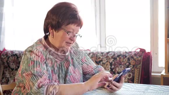 一位老年妇女在手机上写短信她小心翼翼地按在屏幕上发短信视频的预览图