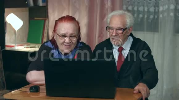 观看笔记本电脑的老年夫妇视频的预览图