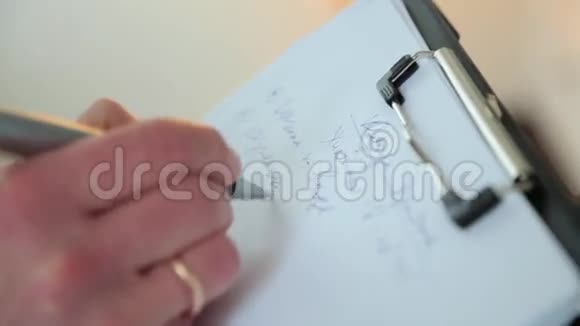 一个戴着结婚戒指的男人在一张纸上记录数据视频的预览图