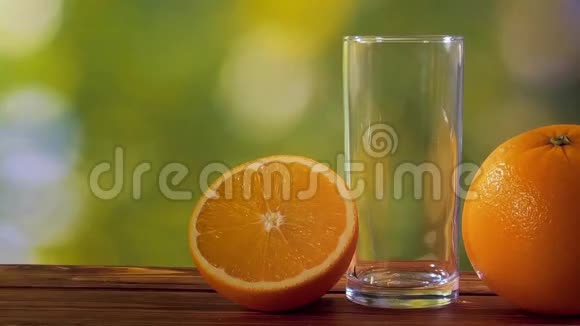 在天然绿色背景下倒入杯中的橙汁视频的预览图