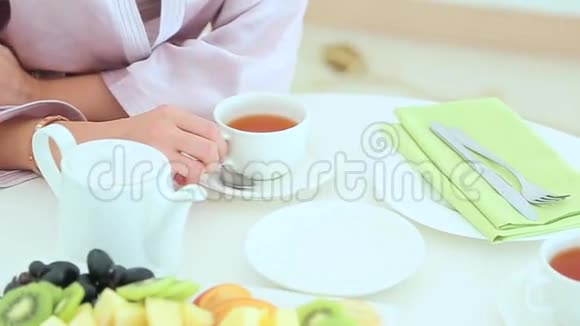穿着浴袍的女人在漂亮的餐桌上喝茶视频的预览图